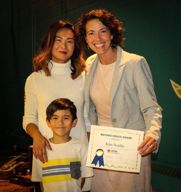 Duluth Mayor Emily Larson presents the Mayor's Choice Award recipient, Kim Nordin, with her winning certificate. Nordin's son (also in the photo) was the subject of the winning image. Photo by Ivy Vainio.